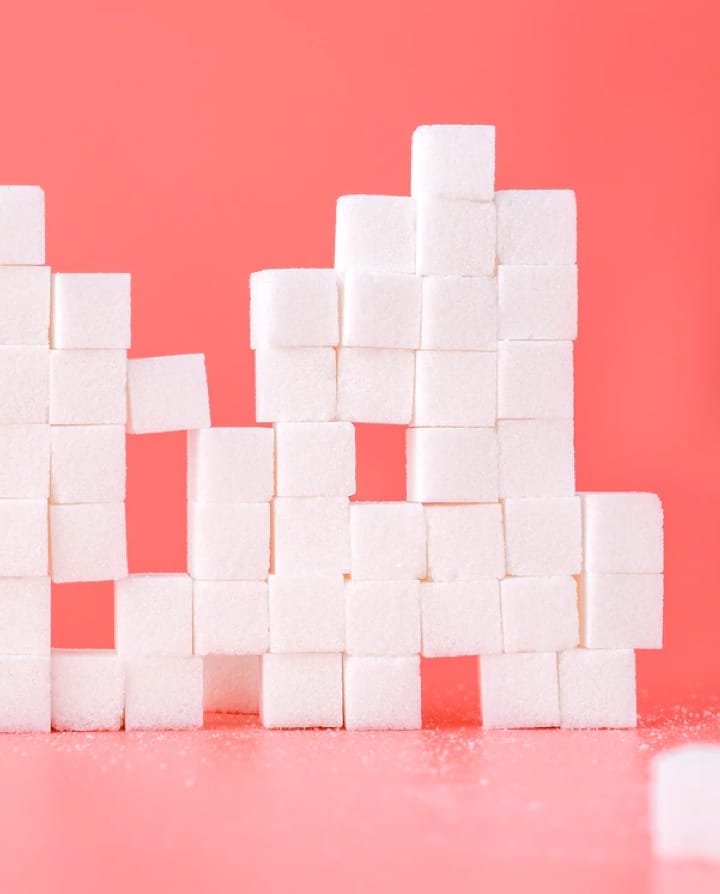 Picture of sugar cubes made into a randomly shaped wall on a pink background