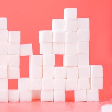 Picture of sugar cubes made into a randomly shaped wall on a pink background